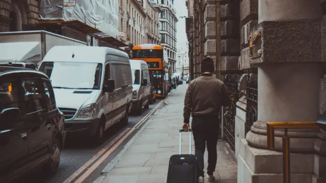 personne marchant dans la rue avec sa valise - voyage